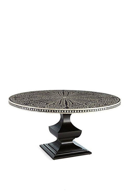 Front angle view of a handmade black and white bone inlay round dining table, showing the floral radial tabletop pattern, contrasting checkerboard border, and solid black geometric pedestal base as a complete dining room furniture piece.