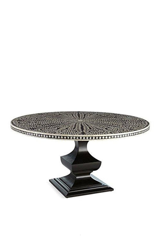 Front angle view of a handmade black and white bone inlay round dining table, showing the floral radial tabletop pattern, contrasting checkerboard border, and solid black geometric pedestal base as a complete dining room furniture piece.