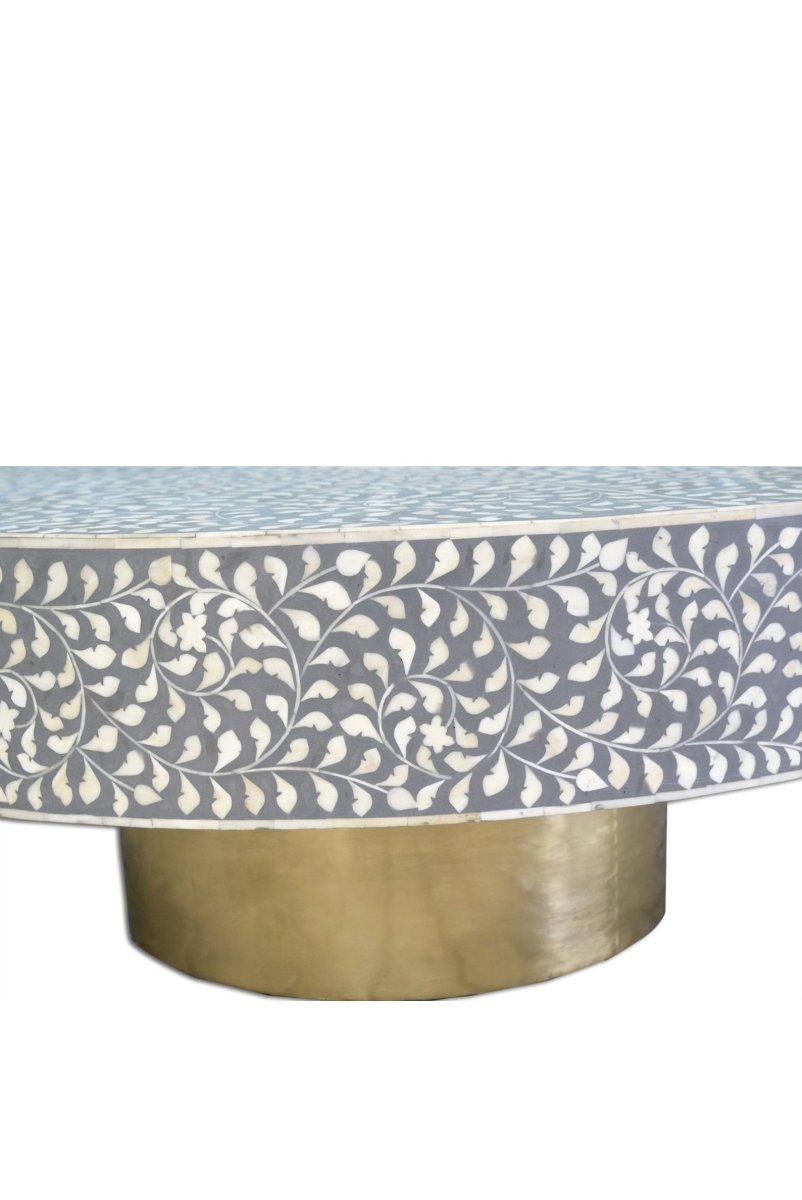 Grey round bone inlay coffee table with a floral pattern and pedestal base.