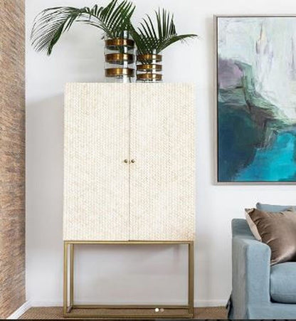 Handmade herringbone bone inlay liquor storage cabinet styled in a modern living room with brass base and tropical plant decor