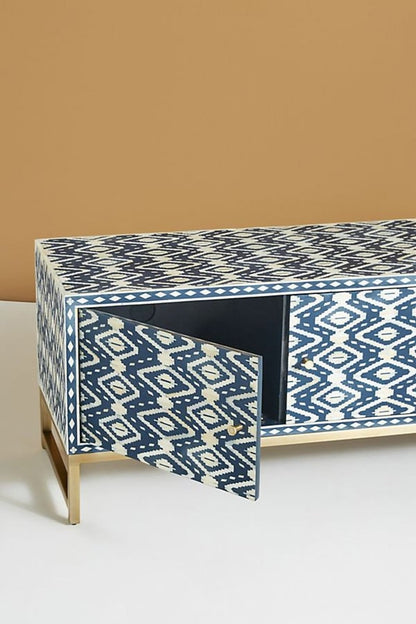 Side angle of a handmade indigo and cream bone inlay TV cabinet, showing the cabinet depth, patterned side and front surfaces, three-door storage design, solid brass handles, flat top, and raised brass base against a neutral background.