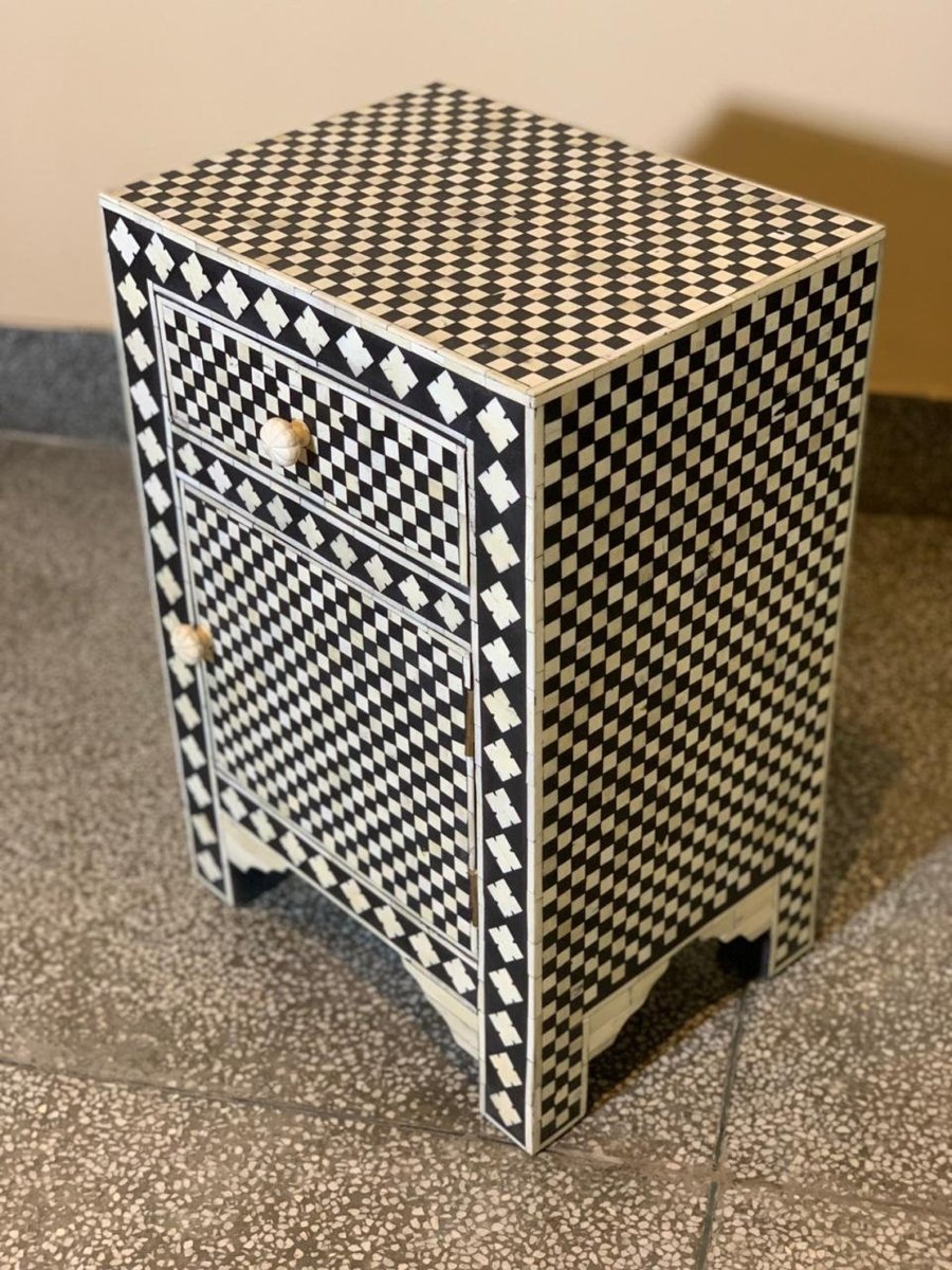 Indian handcrafted bone inlay bedside table with black and white diamond checker pattern covering drawer, cabinet door and side panels, carved bone knobs, three-quarter angle view showing full surface coverage
