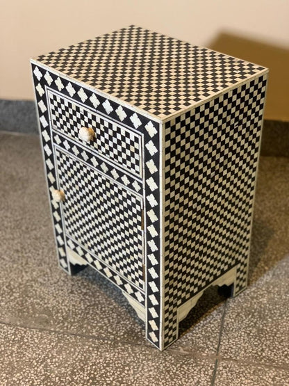 Indian handcrafted bone inlay bedside table with black and white diamond checker pattern covering drawer, cabinet door and side panels, carved bone knobs, three-quarter angle view showing full surface coverage