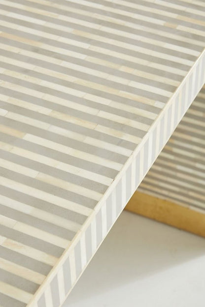 gray and white striped bone inlay entryway table, highlighting the rounded waterfall edge, slim depth, continuous linear pattern, and gold brass-capped feet. This side-positioned product view focuses on the console table’s curved silhouette and inlay surface.