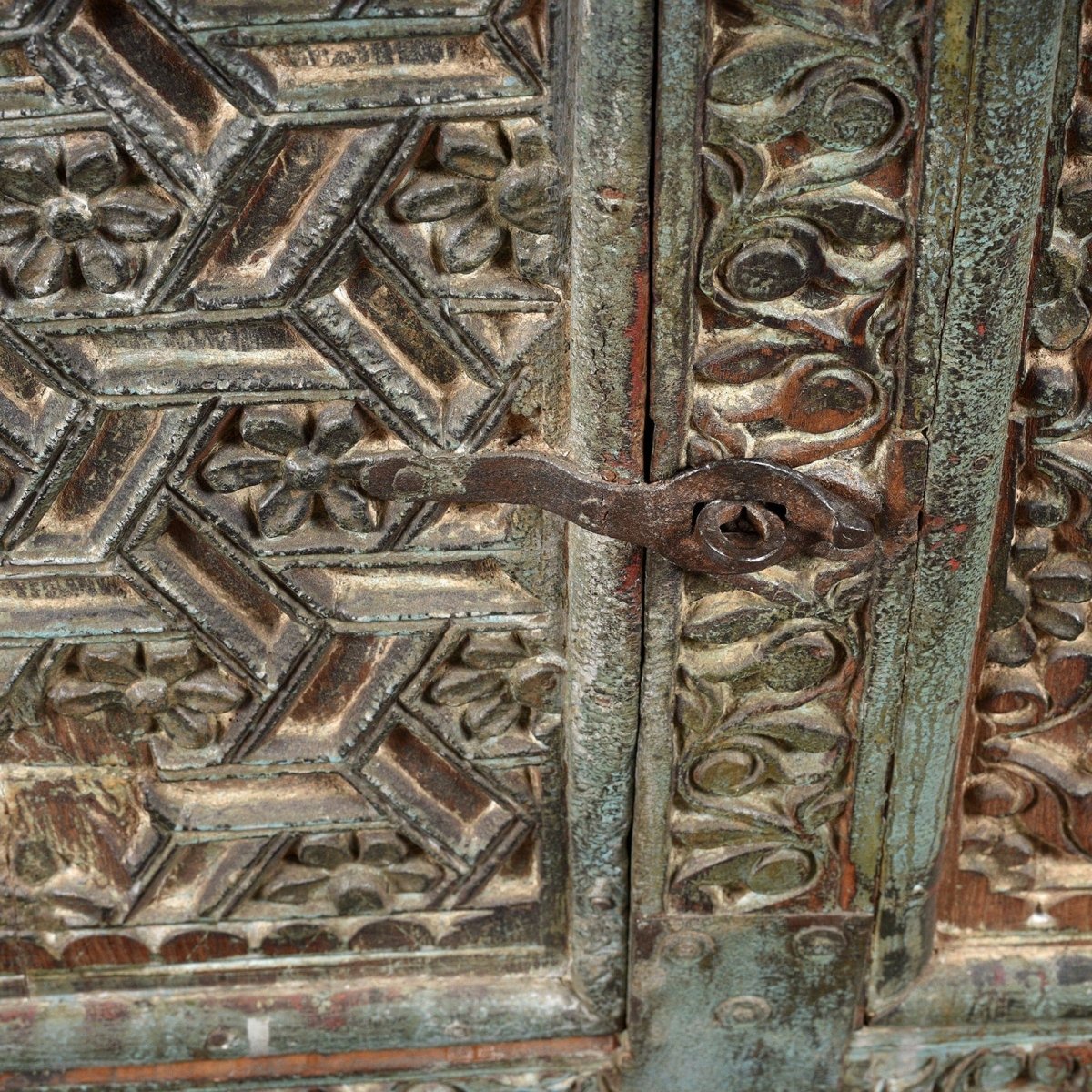 Metal latch hope chest in carved wood, close-up of door hardware showing a horizontal clasp beside geometric flowers.