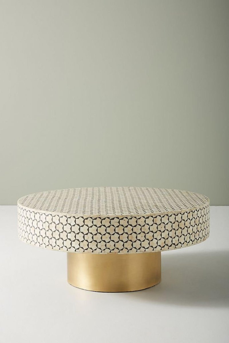 Front angle view of a round black and white bone inlay coffee table with a geometric hexagon star pattern across the tabletop and a solid gold-finished brass pedestal base, showing the complete handcrafted Moroccan design for a living room.