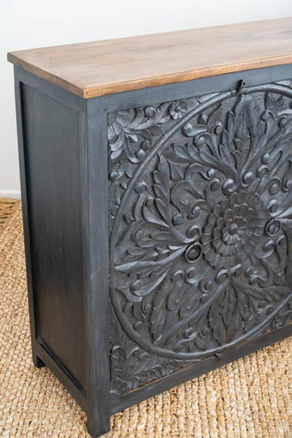 Natural Top Carved Credenza in black wood, shown in corner detail view with its thick top and leafy door carving.
