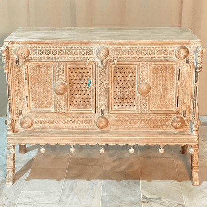 Natural wood carved buffet, front view showing two patterned doors, round wooden accents and hanging ornaments.