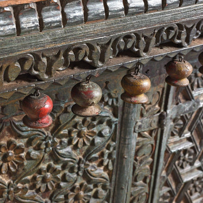 Ornate carved wood buffet, edge detail view showing rounded hanging ornaments beneath scrolling trim with worn green paint.