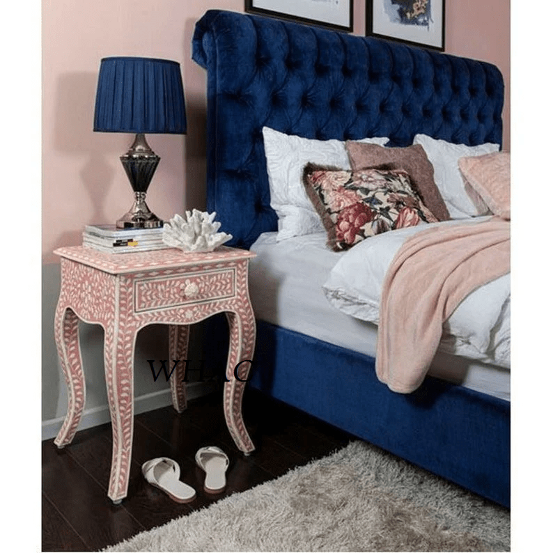 Pink and white bone inlay botanical nightstand with curved cabriole legs and drawer, placed beside a luxury upholstered bed in a romantic bedroom