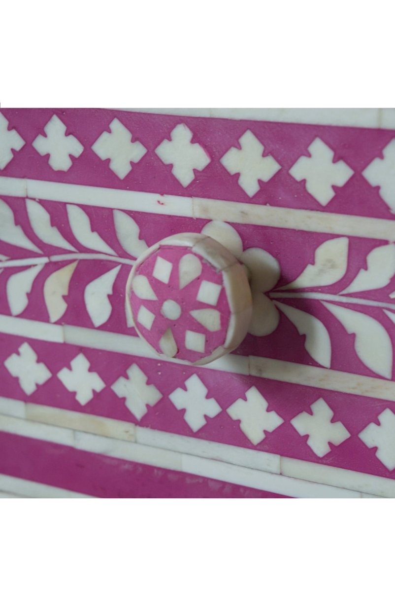 Close up of Pink floral bone inlay bedside cabinet with three drawers, a vine and medallion pattern, and matching knobs.
