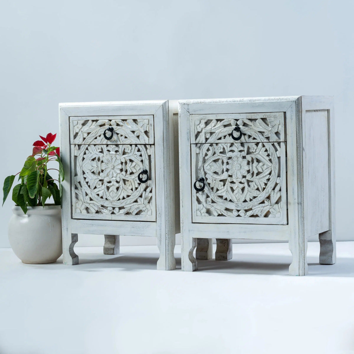 Ring pull night table in rustic wood, front view of two cabinets with floral carving, curved feet and closed doors.