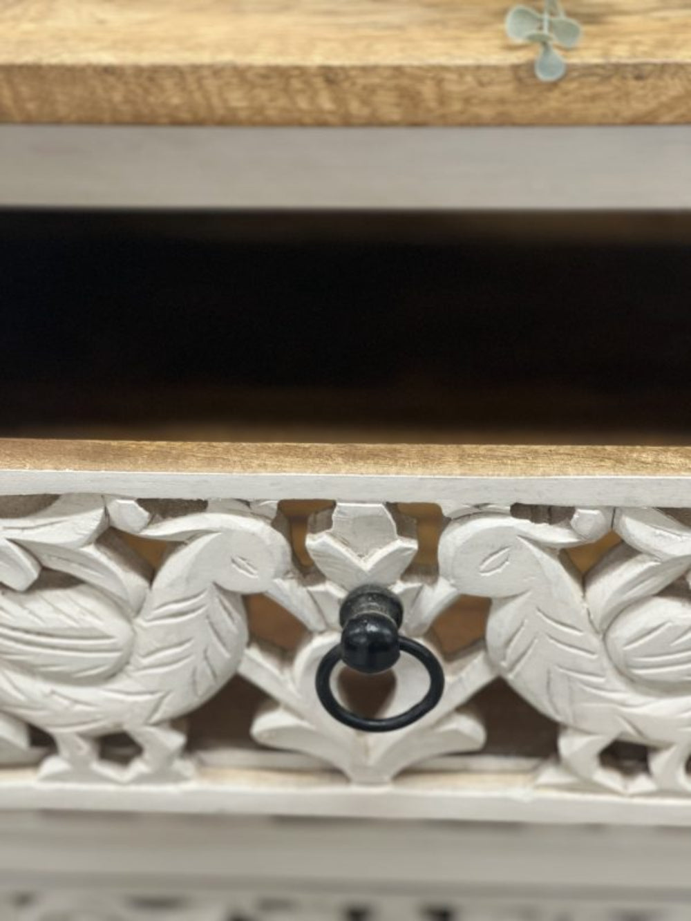 Carved chest of drawers in rustic mango wood, close-up of drawer handle framed by paired peacocks and leafy scrolls.