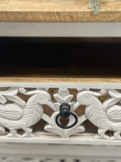 Carved chest of drawers in rustic mango wood, close-up of drawer handle framed by paired peacocks and leafy scrolls.