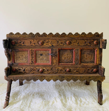 Rustic carved dowry chest in solid wood, front view revealing geometric rosettes, a central latch and weathered trim.