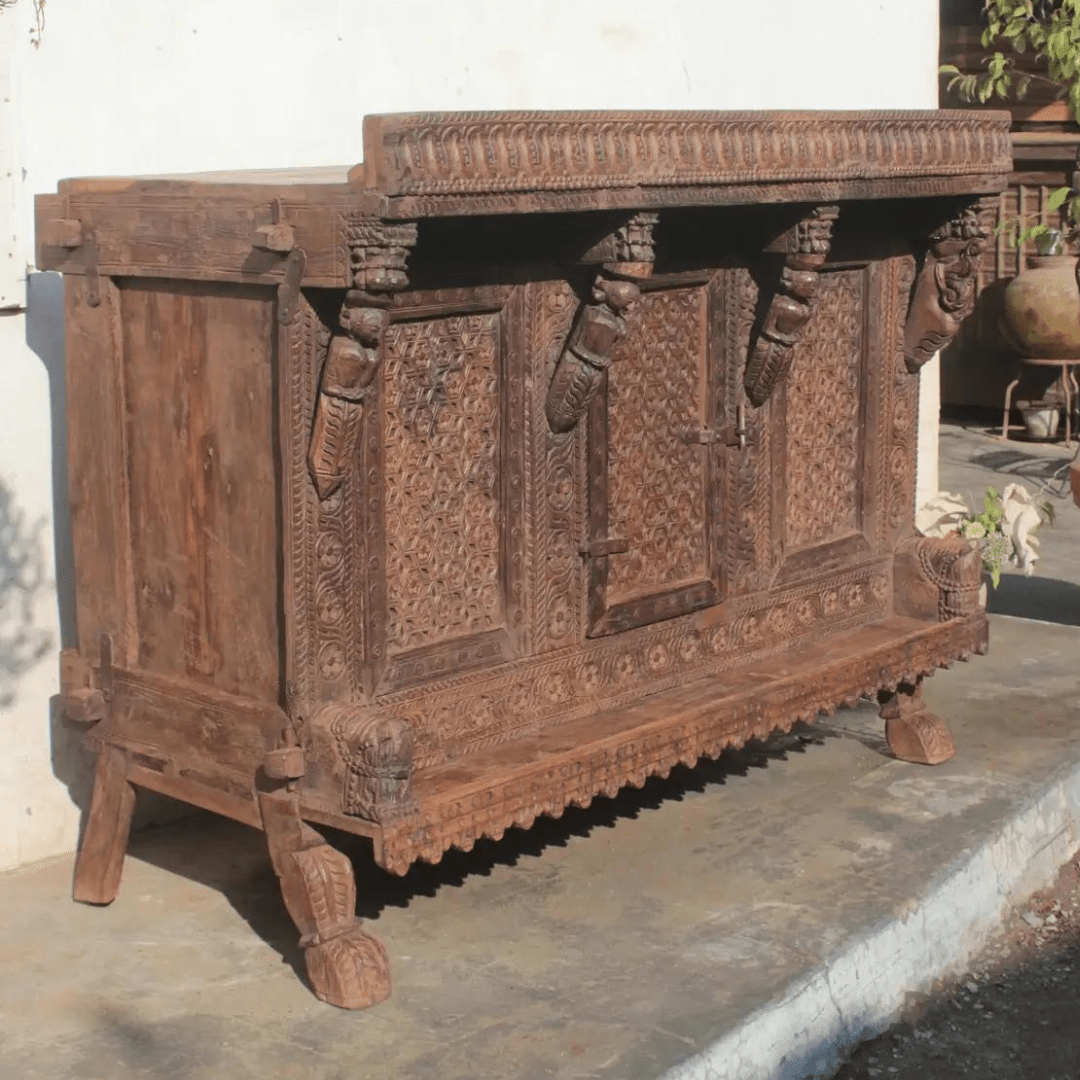 Rustic solid wood hope chest in three-quarter front view, showing its paneled left side, carved door, and shaped feet.