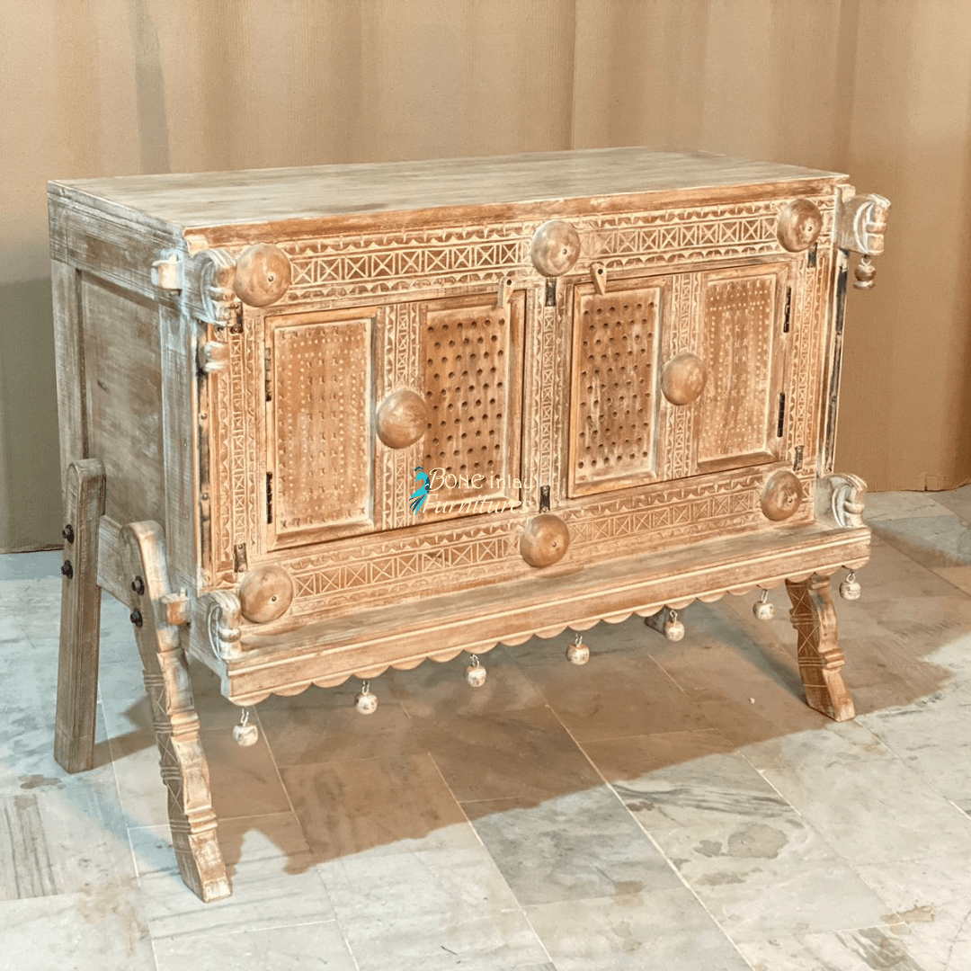 Rustic two-door wood server in natural tones, front view at an angle showing the left side, carved trim and legs.