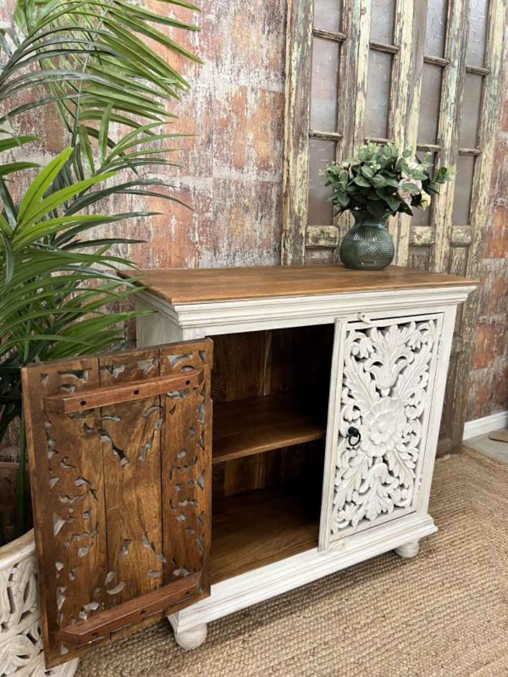 Rustic wood storage cabinet, front view with the left carved door open, revealing a natural wood interior and shelf.
