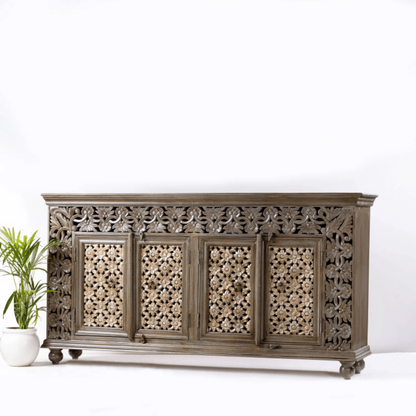 Solid wood carved credenza in a natural finish, angled front view showing the right side, floral doors and short feet.