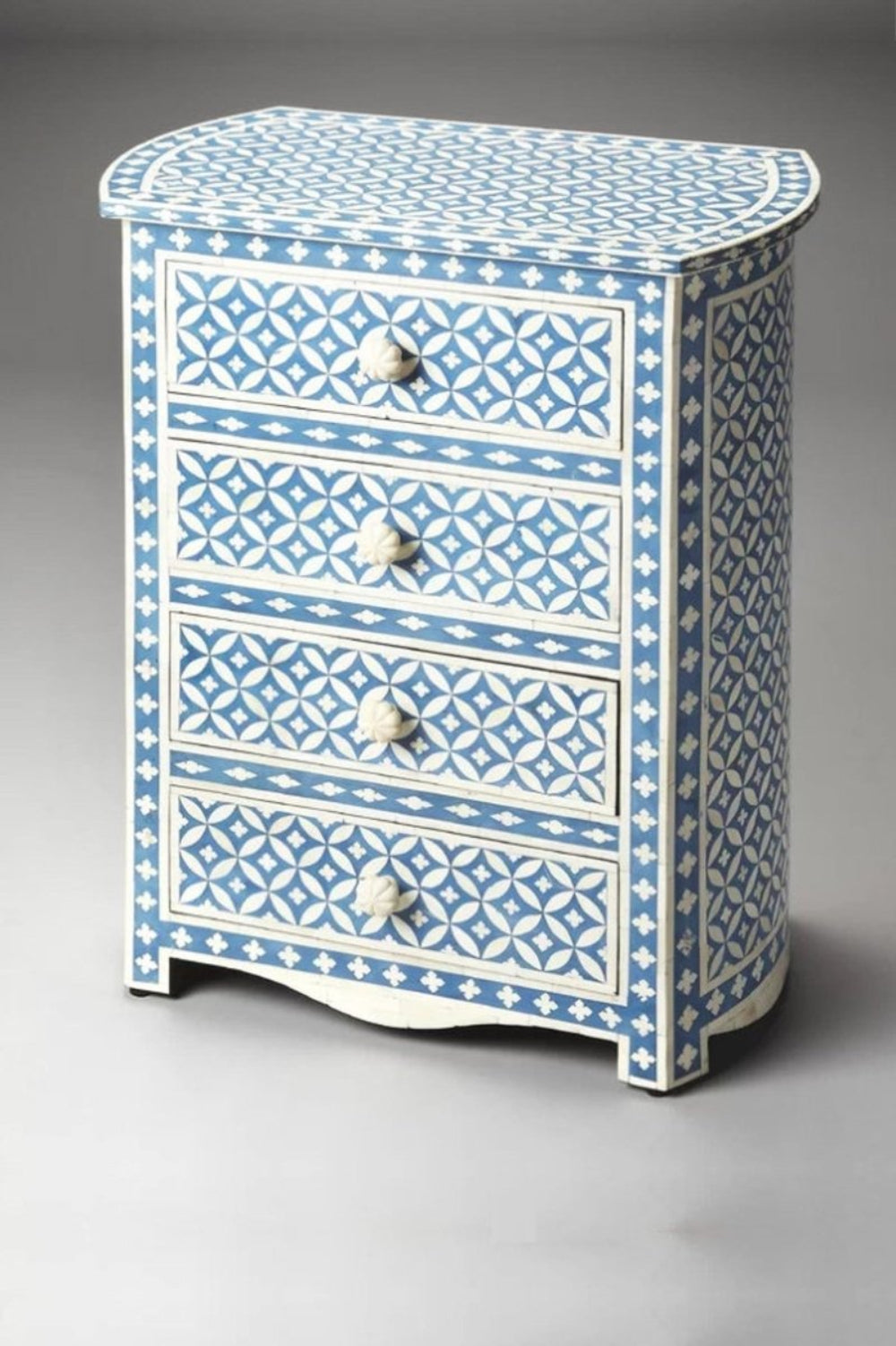 Three-quarter view of a blue bone inlay bedside table with a geometric eye flower pattern, white knobs, and scalloped base.