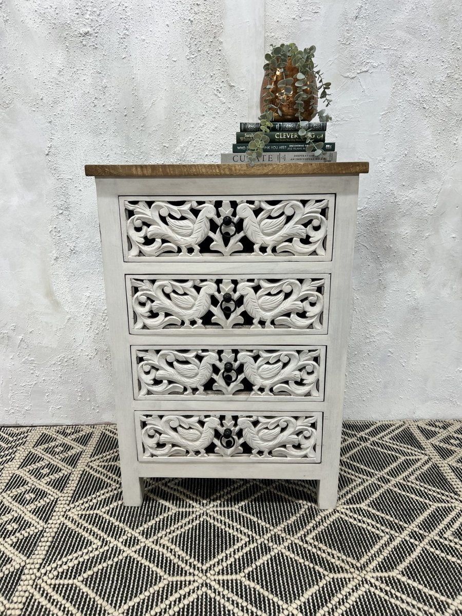 A 4-drawer accent chest made of solid wood with intricate hand-carved peacock patterns, a distressed whitewash finish, and a natural brown wood top.