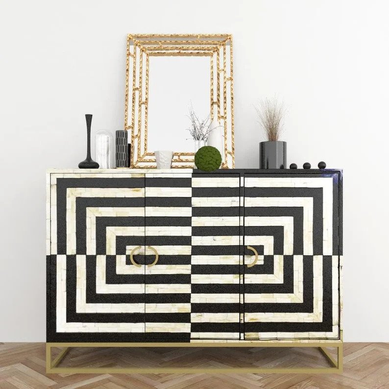 Optical illusion bone inlay buffet table styled with gold mirror, vases and decor on top, bold black white stripe pattern with brass ring pulls, interior vignette