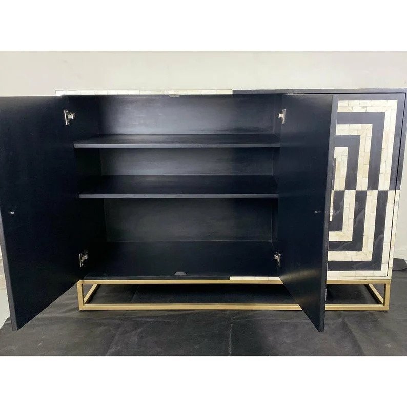 Interior view of handcrafted black and white bone inlay storage cabinet showing two open shelves and adjustable shelf on brass sled base, doors open fully