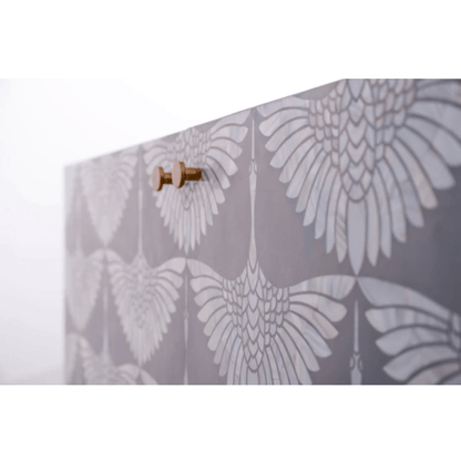 Close detail of bone inlay swan wing pattern on gray sideboard surface with antique brass door knob and handcrafted inlay texture