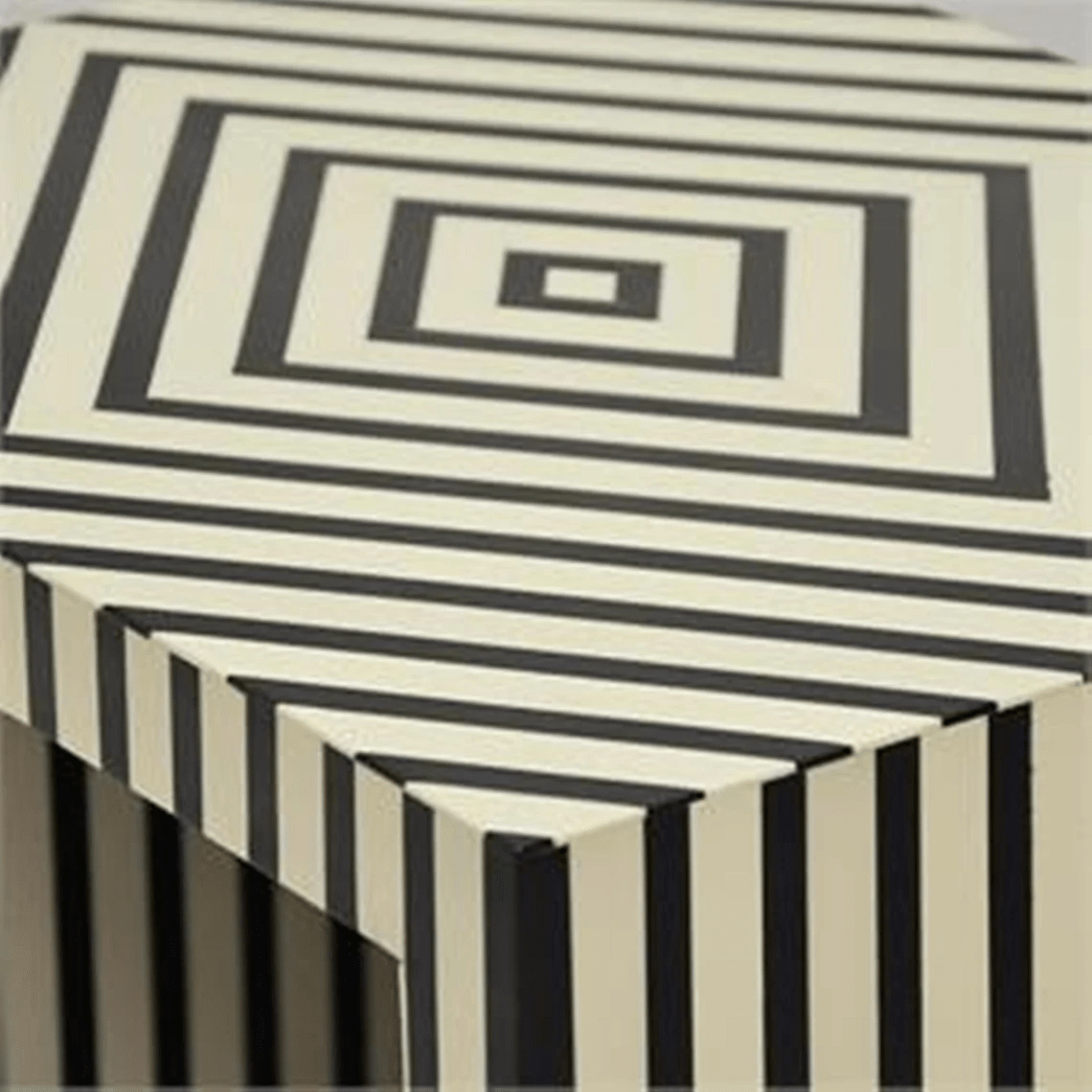 Detail of the bone inlay surface on a nightstand showing bold black and white vertical stripes on the sides and a concentric square border pattern on the top