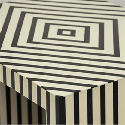 Detail of the bone inlay surface on a nightstand showing bold black and white vertical stripes on the sides and a concentric square border pattern on the top