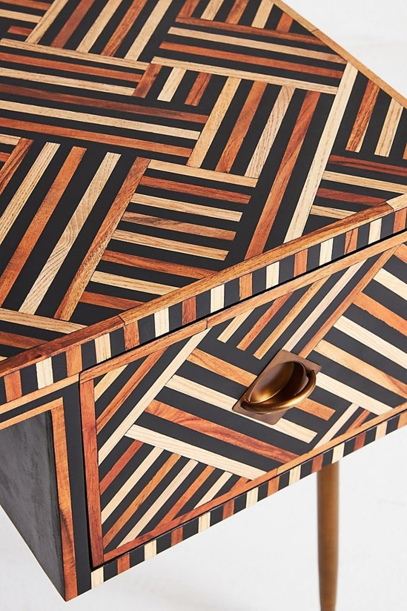 Handmade walnut optical bone inlay work desk shown from an angled top and front corner view, with one drawer open, a dark interior, a brass handle, and layered walnut, cream, and dark linear inlay across the desktop and drawer front.