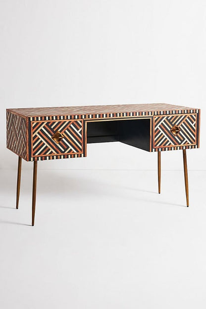Handmade walnut optical bone inlay work desk shown in a straight-on front view, with warm walnut, cream, and dark geometric inlay across the top and two drawer fronts, brass handles, slim tapered legs, and a clean white studio background.