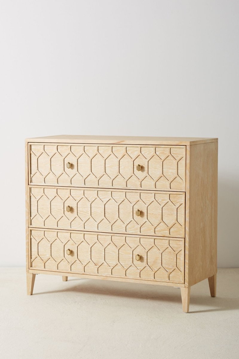 A 3-drawer solid wood dresser with a hand-carved textured trellis pattern in a light natural finish, featuring hexagonal brass knobs and tapered legs.