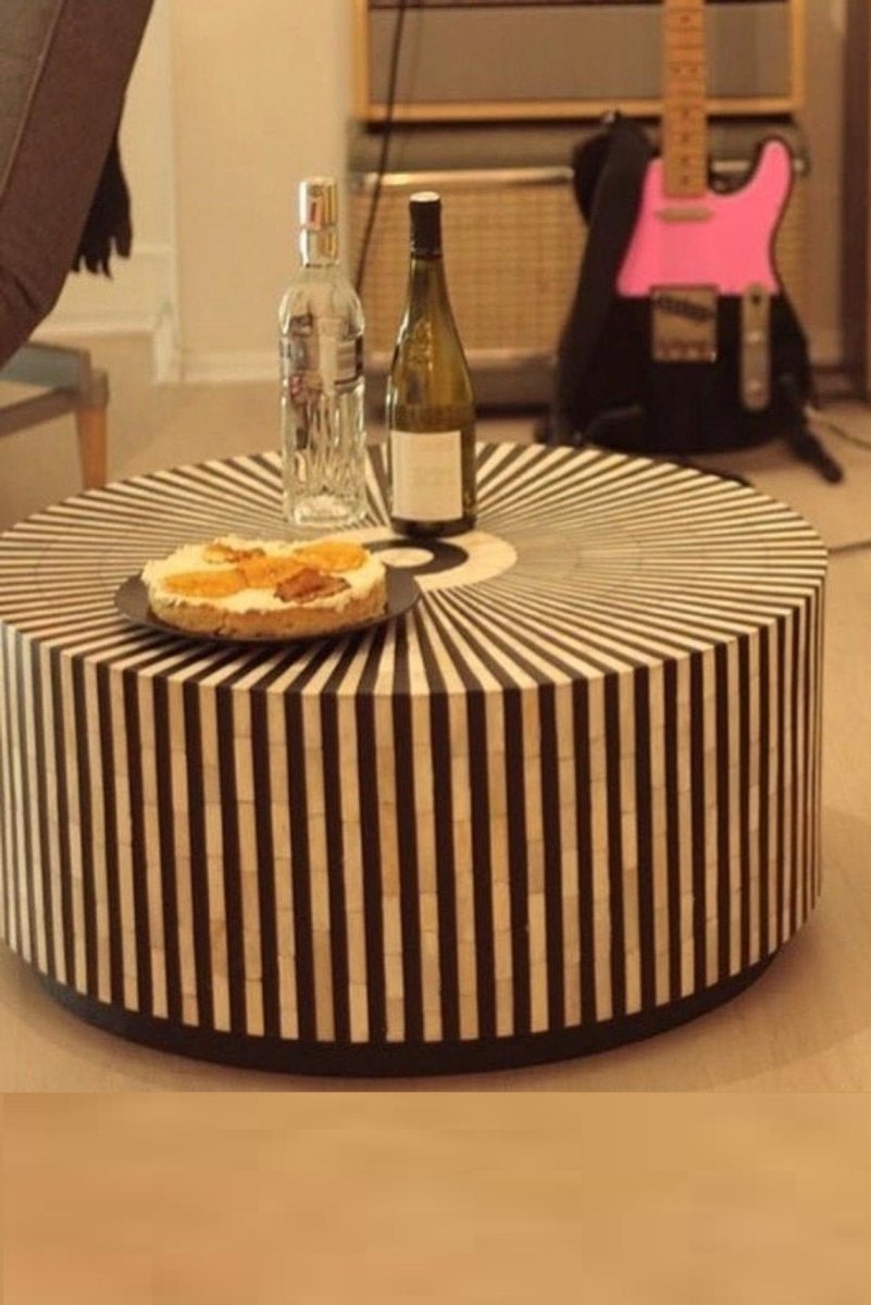 Round black and white bone inlay coffee table with repeating stripe pattern shown in a side angle product view.