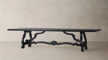 Large matte black solid wood dining table featuring dramatic hand-carved scroll pedestal legs and a traditional Baroque trestle base.